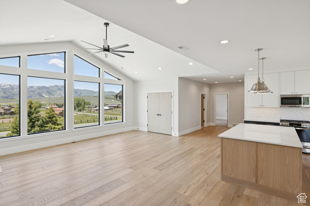 Kitchen with appliances with stainless steel finishes, open floor plan, a mountain view, decorative light fixtures, and recessed lighting