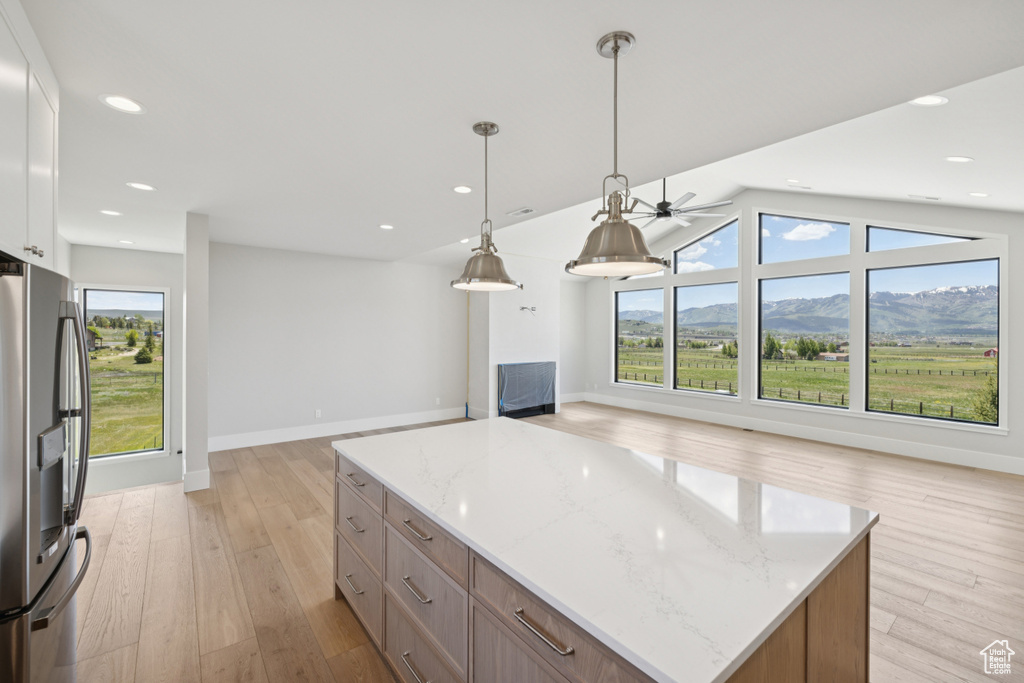 Kitchen with freestanding refrigerator, open floor plan, light wood finished floors, light stone countertops, and a fireplace