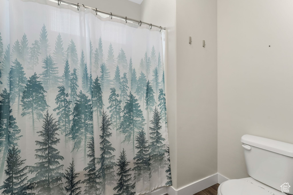 Full bath with wood finished floors and curtained shower