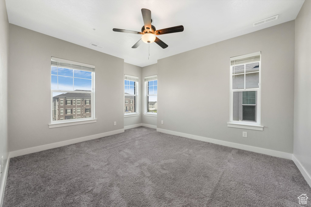 Empty room with a ceiling fan and carpet