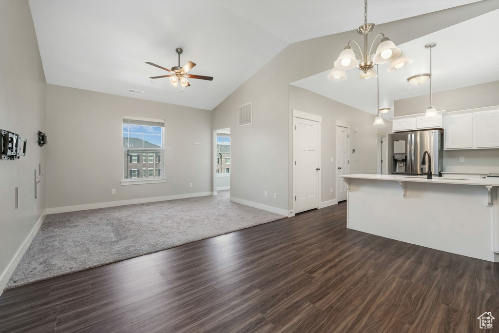 Kitchen featuring stainless steel refrigerator with ice dispenser, a ceiling fan, light countertops, open floor plan, and a breakfast bar area