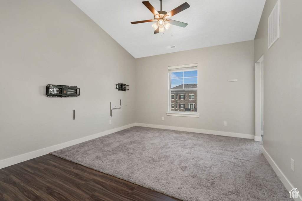 Carpeted empty room featuring vaulted ceiling and a ceiling fan