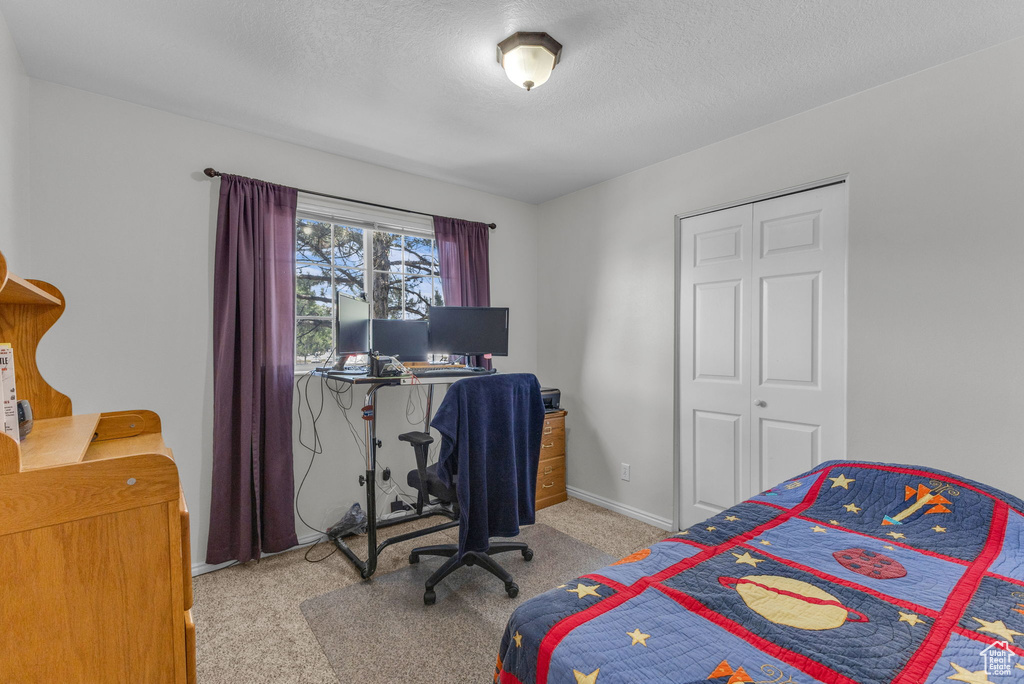Carpeted bedroom featuring a textured ceiling and an office area