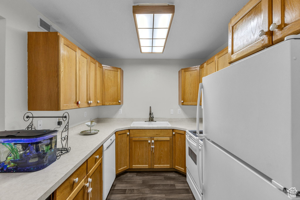 Kitchen with white appliances, dark wood-style flooring, and light countertops