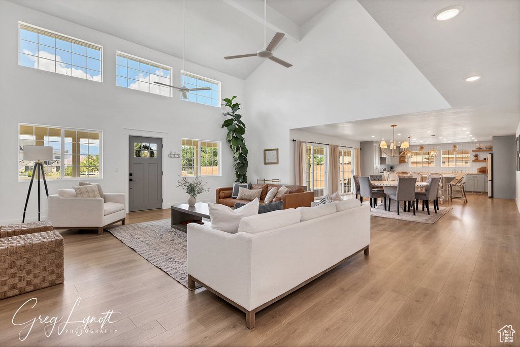 Living area with high vaulted ceiling, a chandelier, light wood-style floors, ceiling fan, and recessed lighting