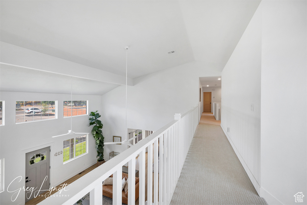 Hallway with light carpet, recessed lighting, and high vaulted ceiling