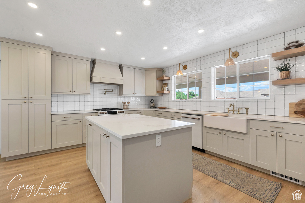 Kitchen with open shelves, custom range hood, dishwasher, tasteful backsplash, and a kitchen island
