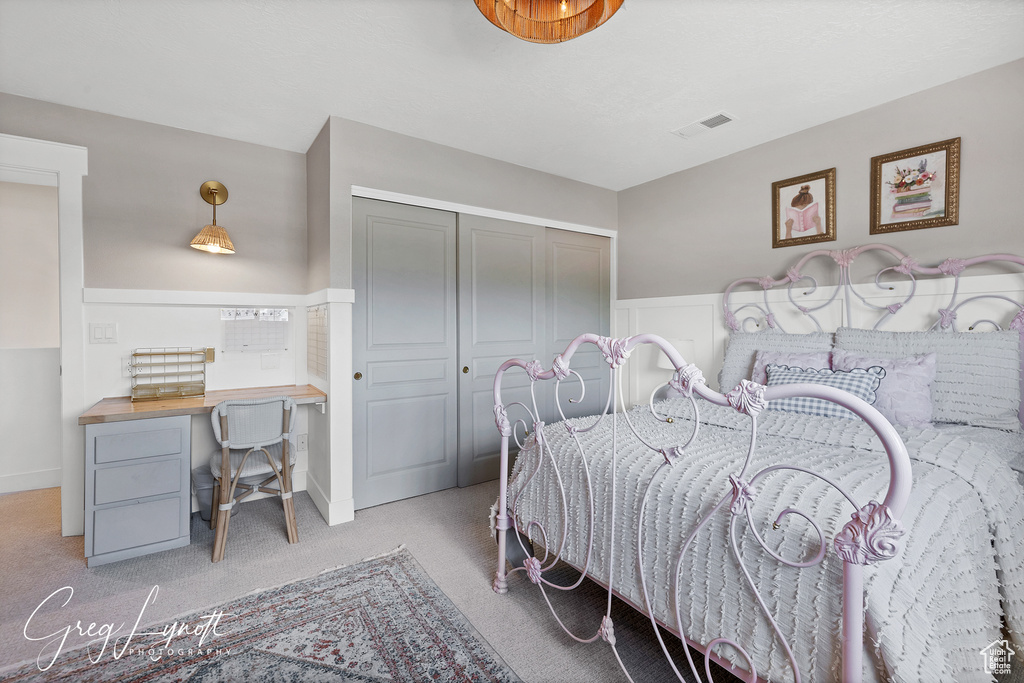 Carpeted bedroom with a wainscoted wall, a closet, and a desk