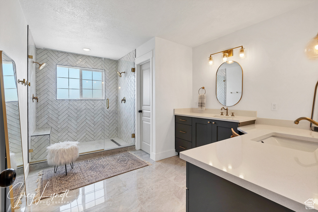 Full bath with vanity, a tile shower, a textured ceiling, and marble finish floors