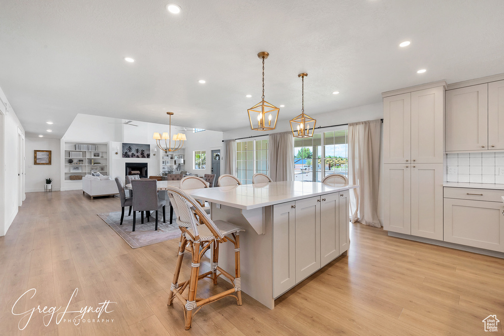 Kitchen with a chandelier, recessed lighting, a kitchen bar, light wood-style floors, and light countertops