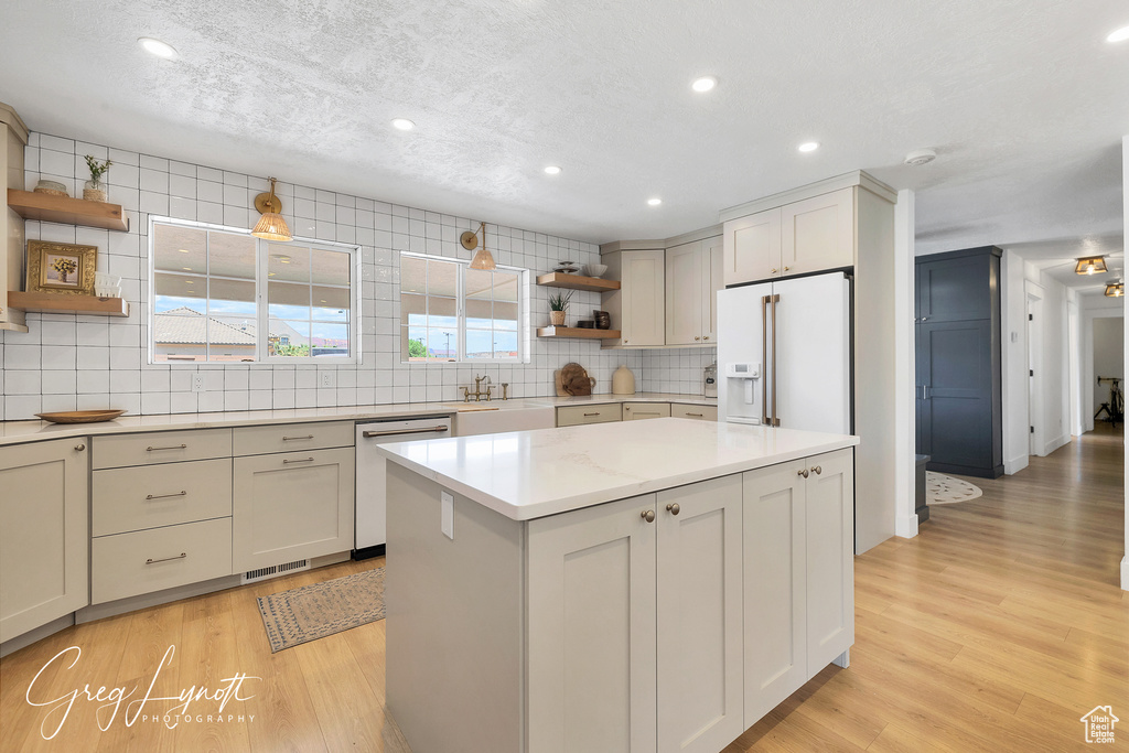 Kitchen featuring open shelves, white fridge with ice dispenser, dishwasher, backsplash, and light wood-style floors