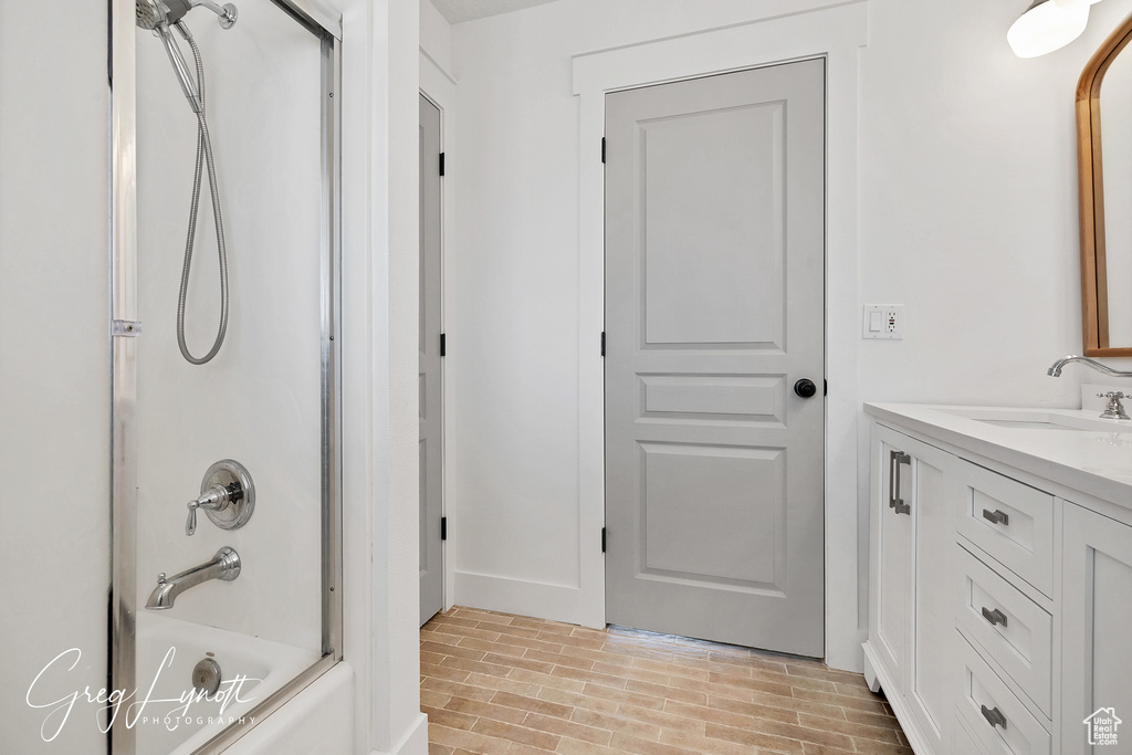 Bathroom with tub / shower combination, vanity, and brick patterned floors