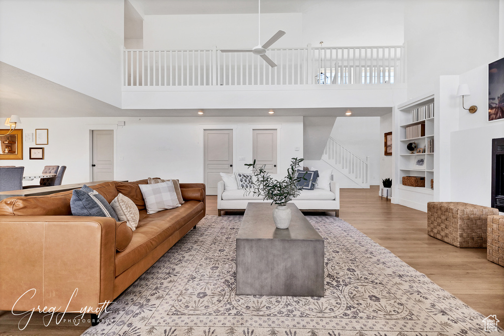 Living area featuring a towering ceiling, wood finished floors, stairway, and ceiling fan
