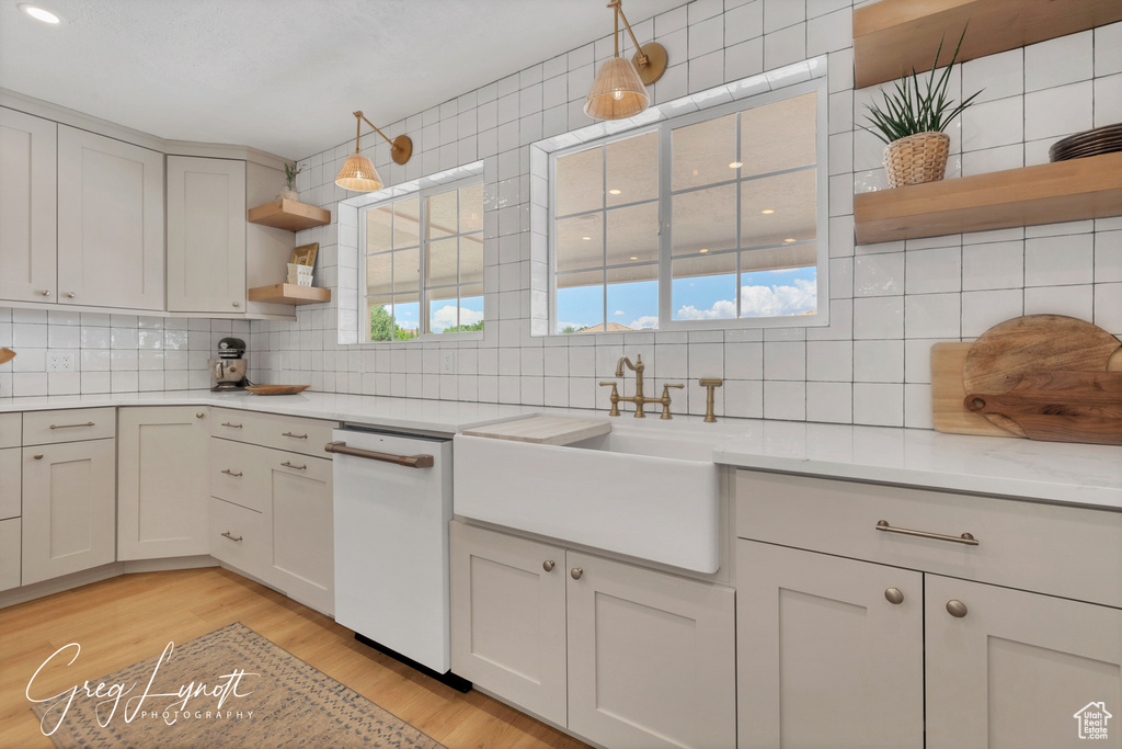 Kitchen featuring open shelves, dishwasher, backsplash, and light countertops