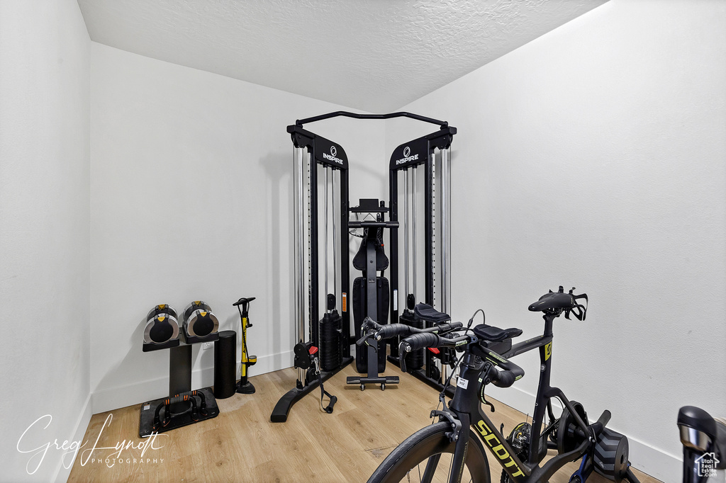 Exercise room featuring wood finished floors and a textured ceiling