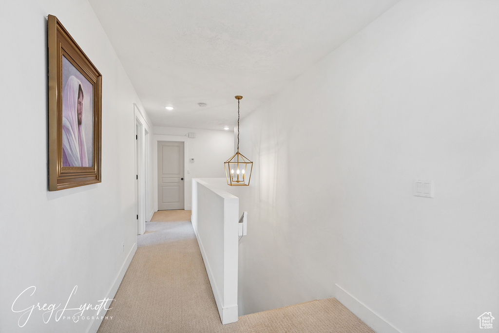 Hallway featuring an upstairs landing, light colored carpet, a chandelier, and recessed lighting