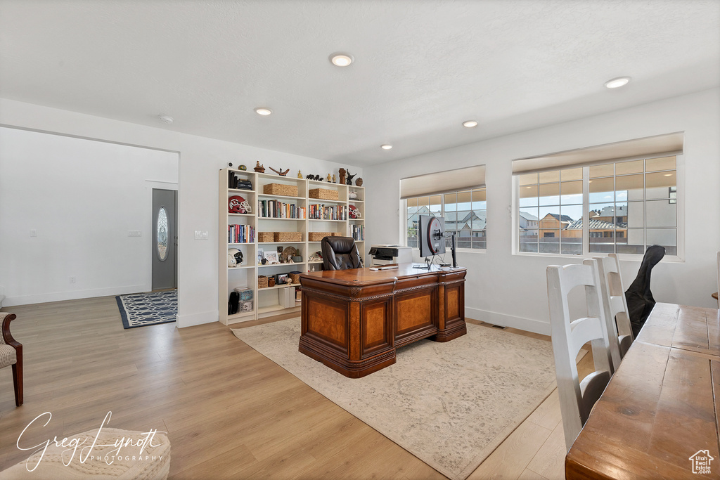 Home office with light wood finished floors and recessed lighting