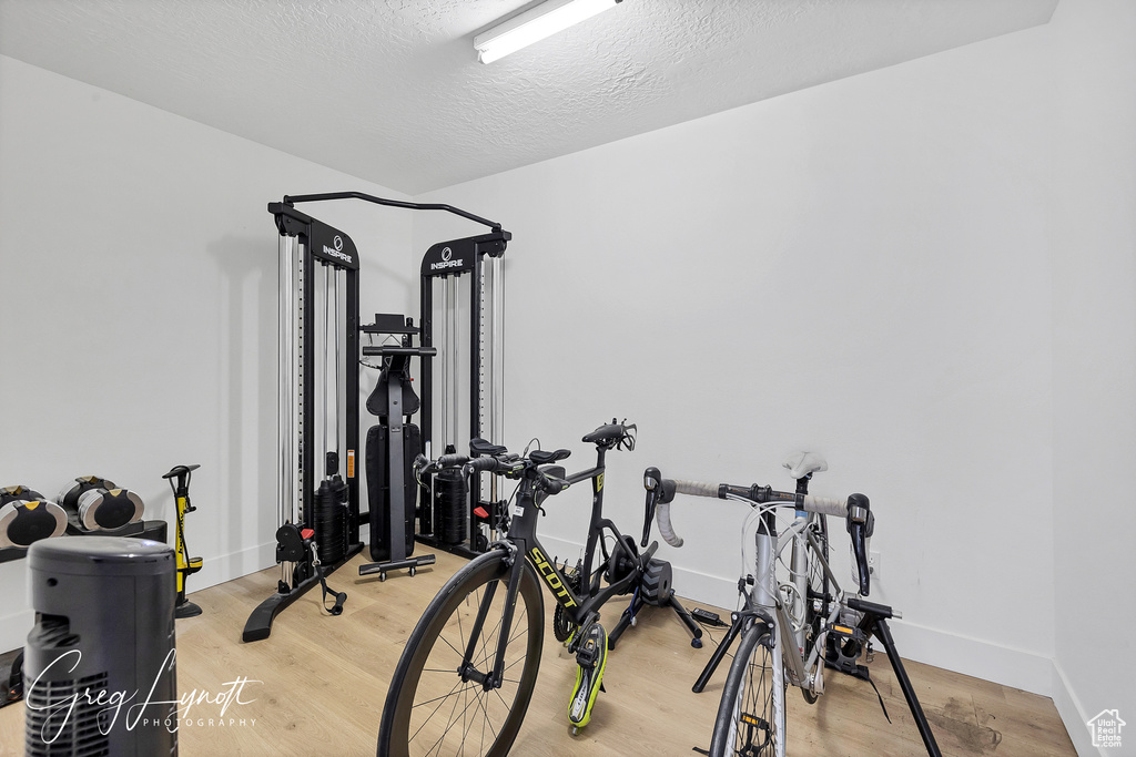Workout room featuring light wood finished floors and a textured ceiling