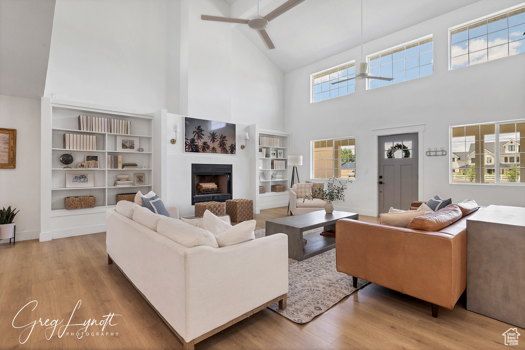 Living area with high vaulted ceiling, ceiling fan, a fireplace, wood finished floors, and beam ceiling