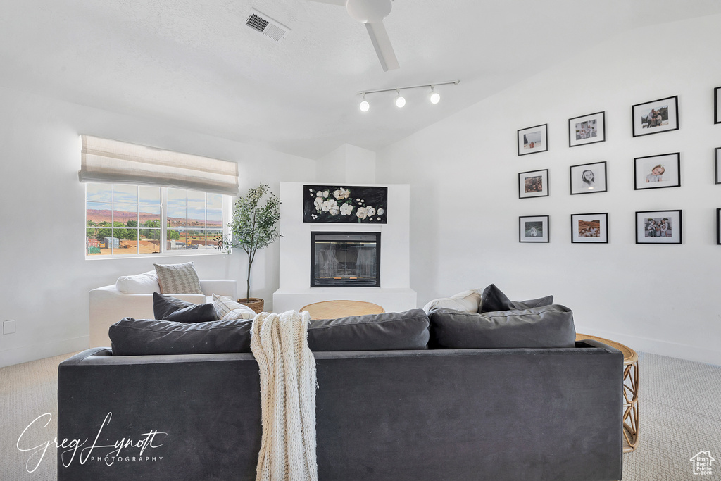 Living room featuring carpet, lofted ceiling, a glass covered fireplace, and rail lighting