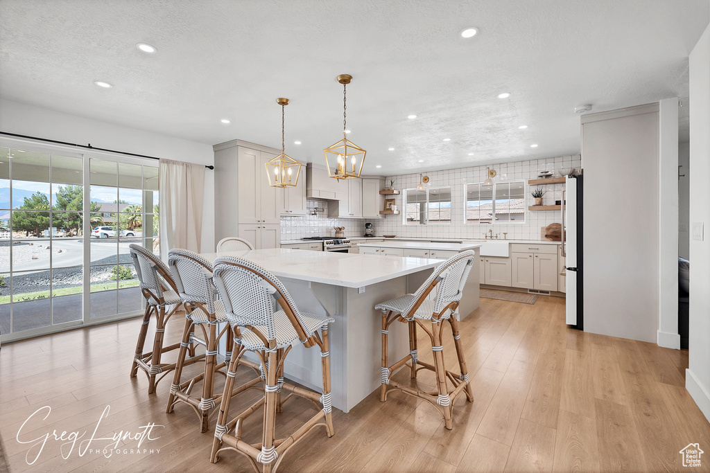 Kitchen featuring recessed lighting, open shelves, light countertops, freestanding refrigerator, and tasteful backsplash