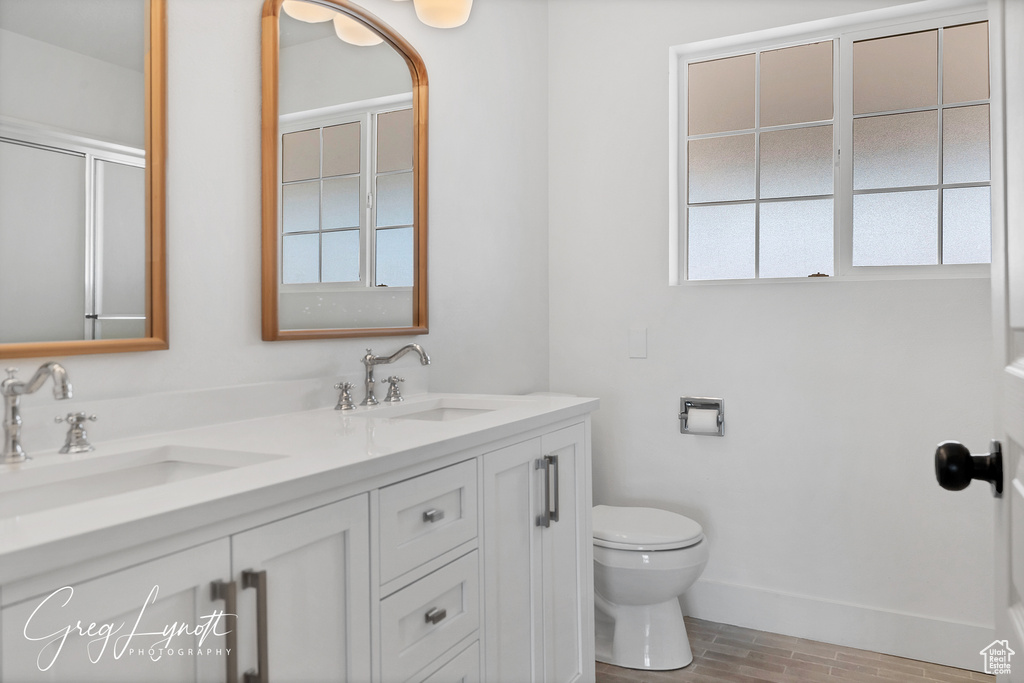 Full bath featuring double vanity, plenty of natural light, wood finished floors, and a shower