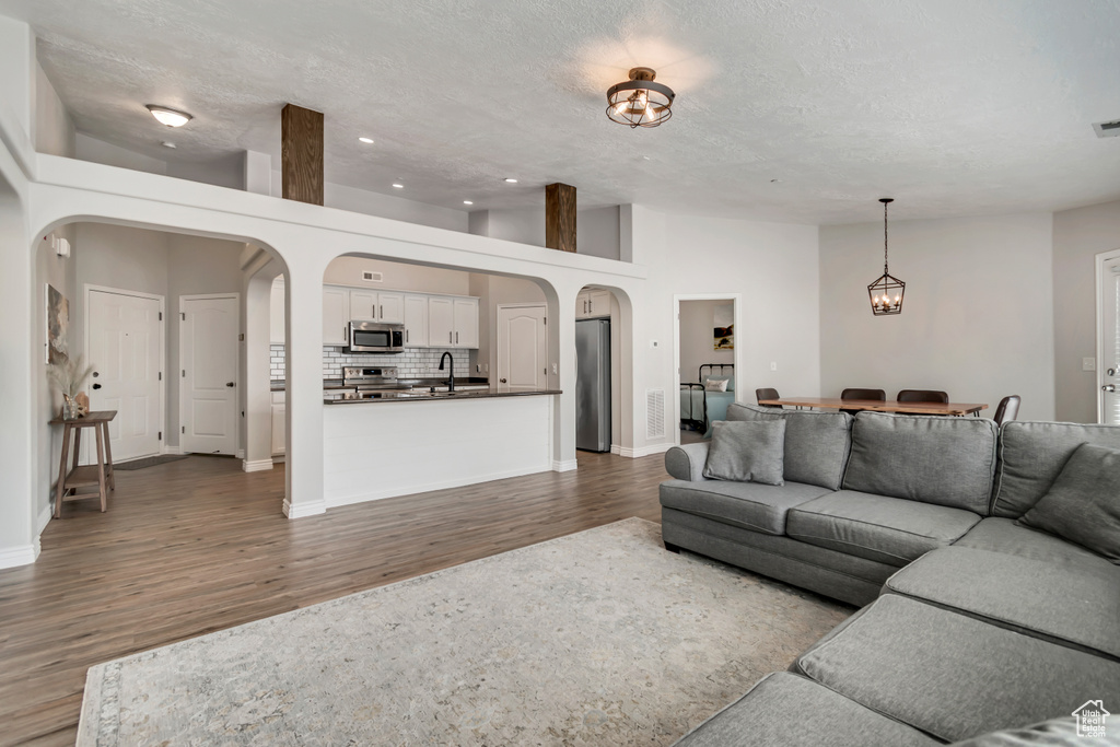 Living room featuring arched walkways, dark wood-type flooring, recessed lighting, and a textured ceiling