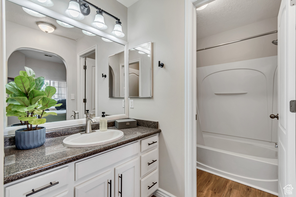 Full bath with vanity, bathing tub / shower combination, and wood finished floors
