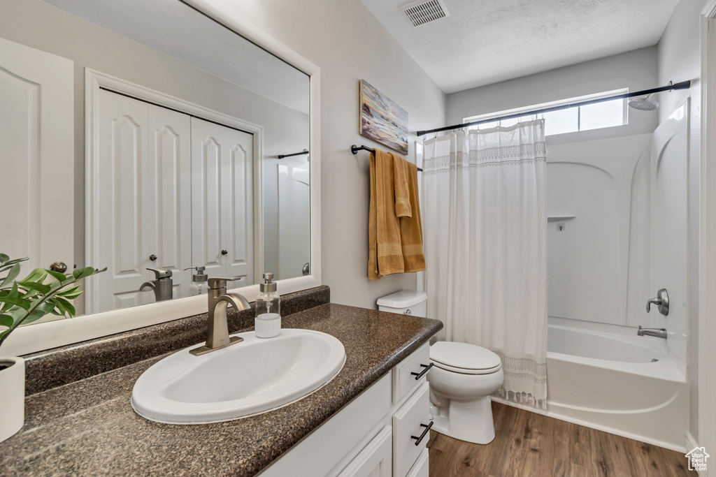 Bathroom featuring vanity, shower / bathtub combination with curtain, and wood finished floors
