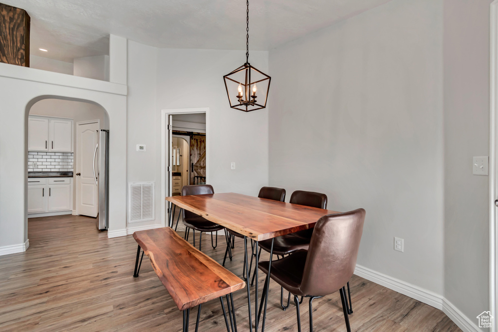Dining area featuring arched walkways, light wood finished floors, and a chandelier