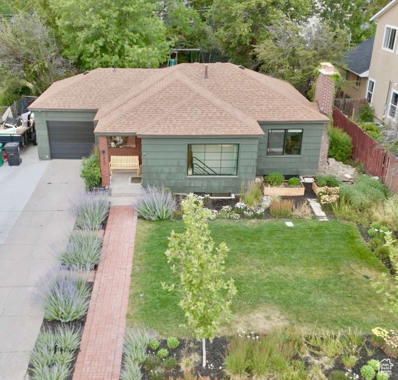 Ranch-style home featuring a shingled roof, concrete driveway, an attached garage, and a chimney