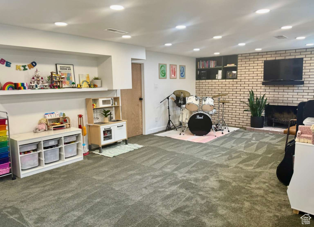 Game room featuring carpet, recessed lighting, brick wall, and a brick fireplace