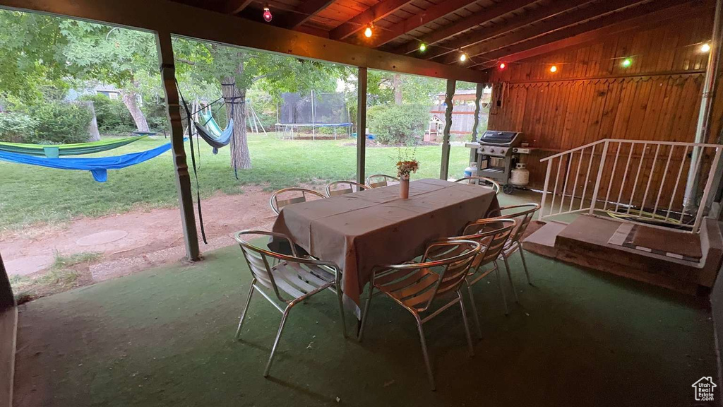 View of patio featuring a trampoline, outdoor dining area, and a grill