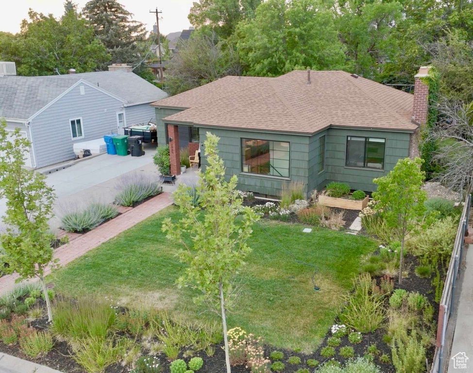 View of front of house featuring a chimney, a shingled roof, and a front yard