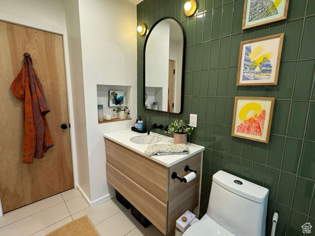Half bathroom featuring tile patterned flooring, vanity, and tile walls