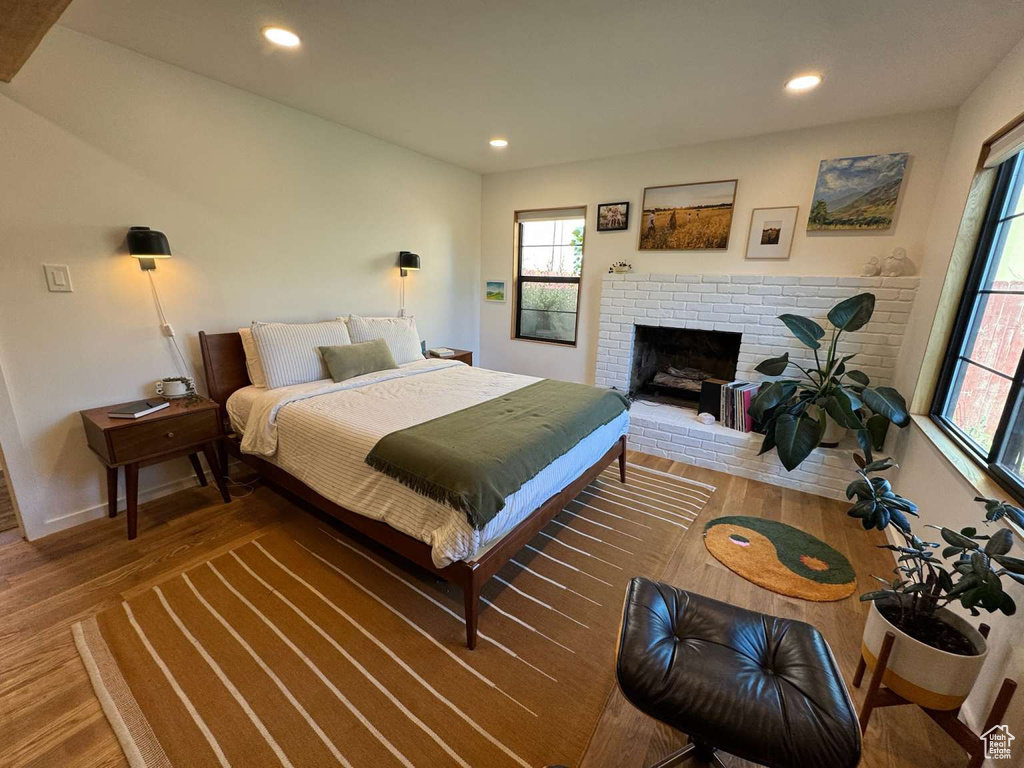 Bedroom featuring multiple windows, wood finished floors, recessed lighting, and a brick fireplace