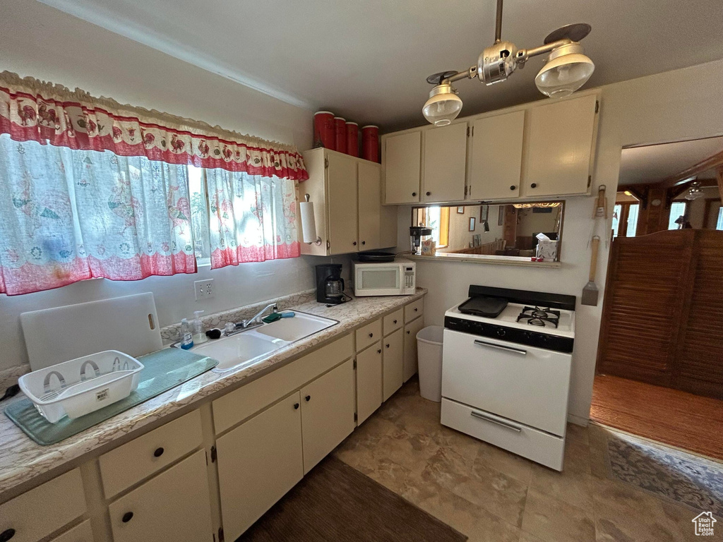 Kitchen featuring white appliances, light countertops, and white cabinets