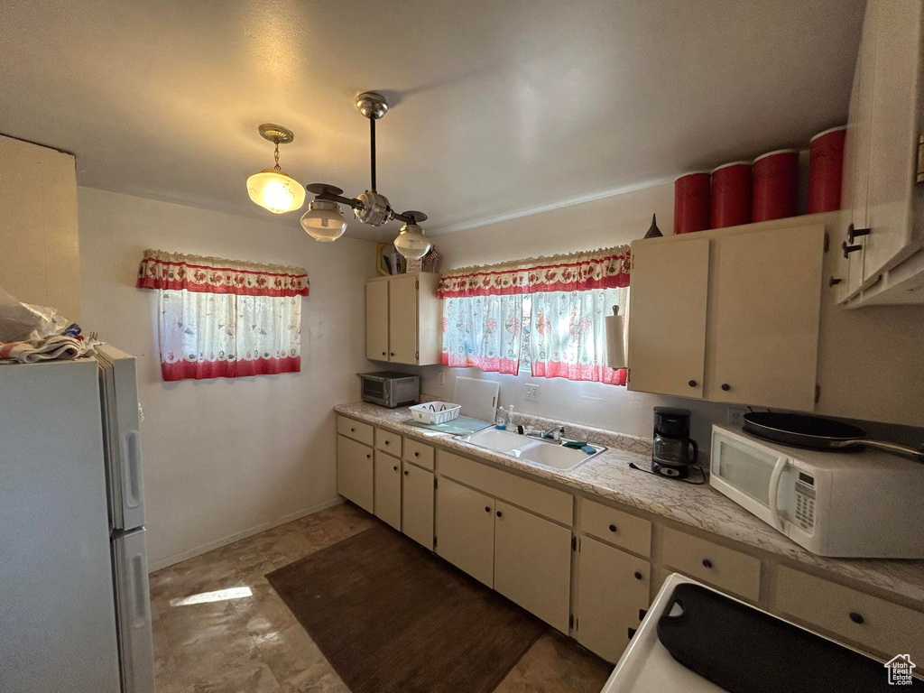 Kitchen featuring white appliances, light countertops, and white cabinetry