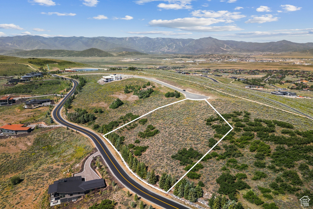 Aerial view of property and surrounding area with property parcel outlined, a mountain backdrop, and rural landscape