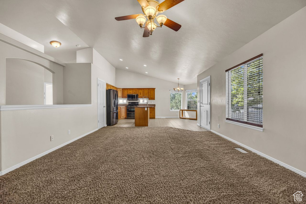 Unfurnished living room featuring vaulted ceiling, a chandelier, ceiling fan, light carpet, and recessed lighting