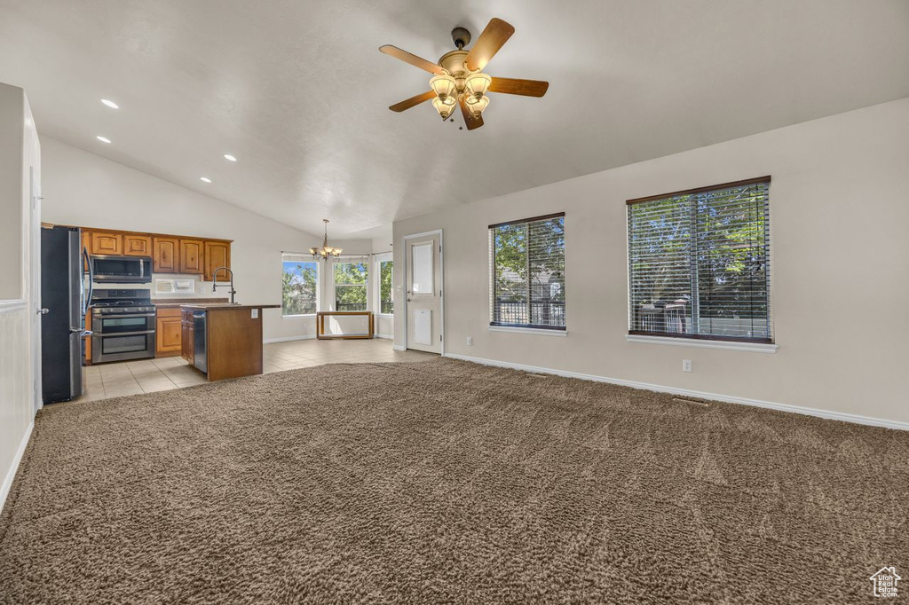 Kitchen with open floor plan, range with two ovens, freestanding refrigerator, a chandelier, and lofted ceiling