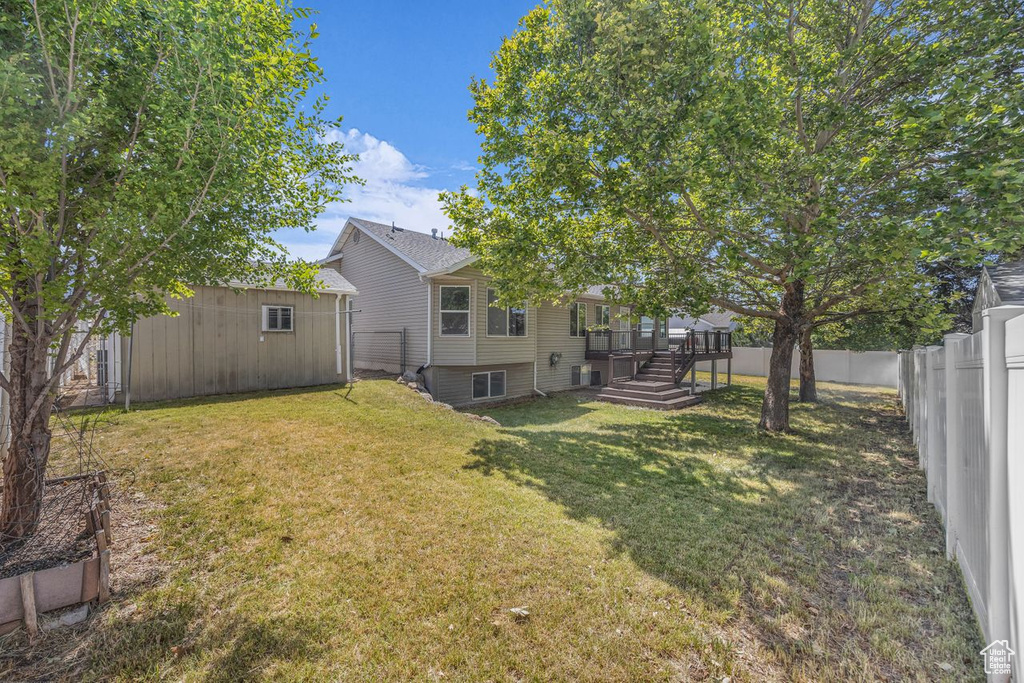Fenced backyard featuring an outdoor structure and a wooden deck