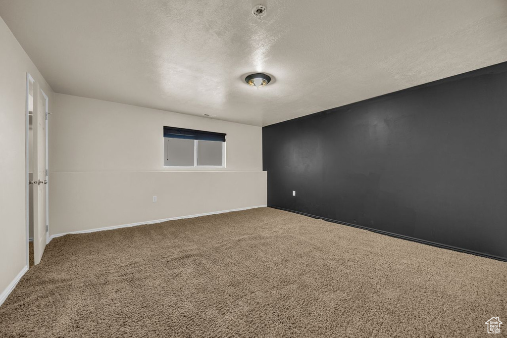 Carpeted empty room featuring a textured ceiling and baseboards