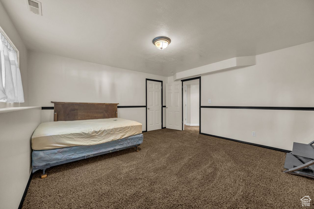 Bedroom featuring dark carpet and baseboards