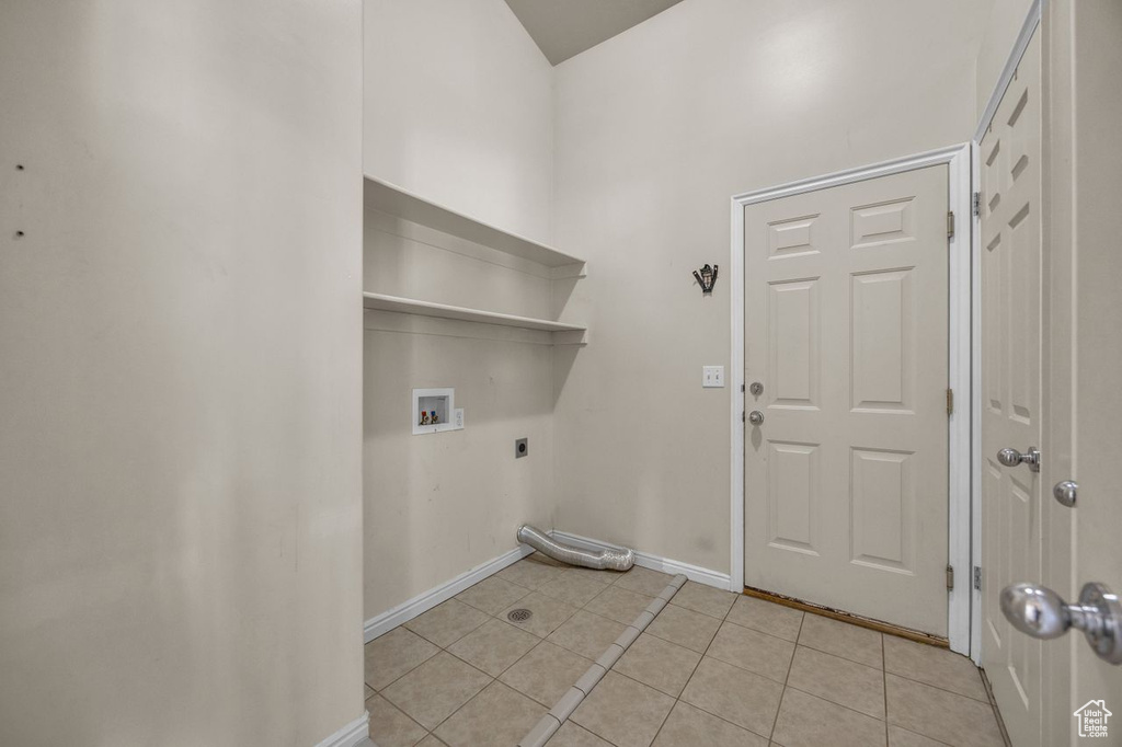 Laundry room with hookup for an electric dryer, washer hookup, light tile patterned floors, and a towering ceiling
