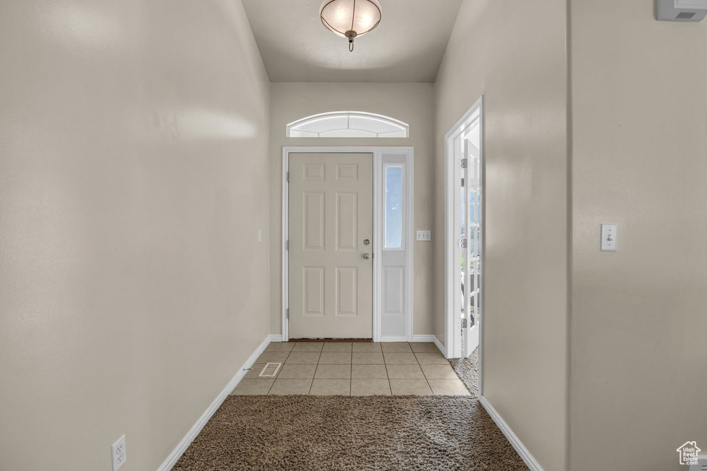 Foyer entrance featuring light tile patterned flooring and light colored carpet