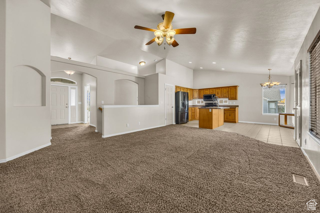 Unfurnished living room with light colored carpet, a chandelier, high vaulted ceiling, a ceiling fan, and recessed lighting