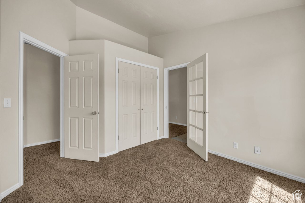 Unfurnished bedroom with carpet floors, french doors, and a closet