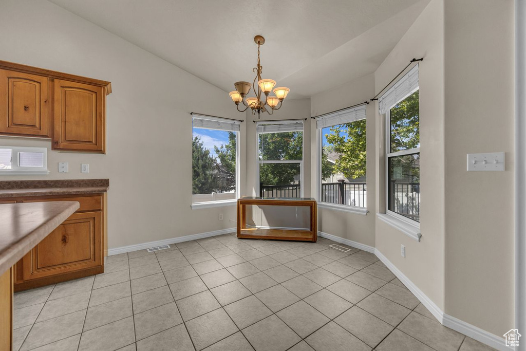 Unfurnished dining area with a chandelier, lofted ceiling, and light tile patterned floors