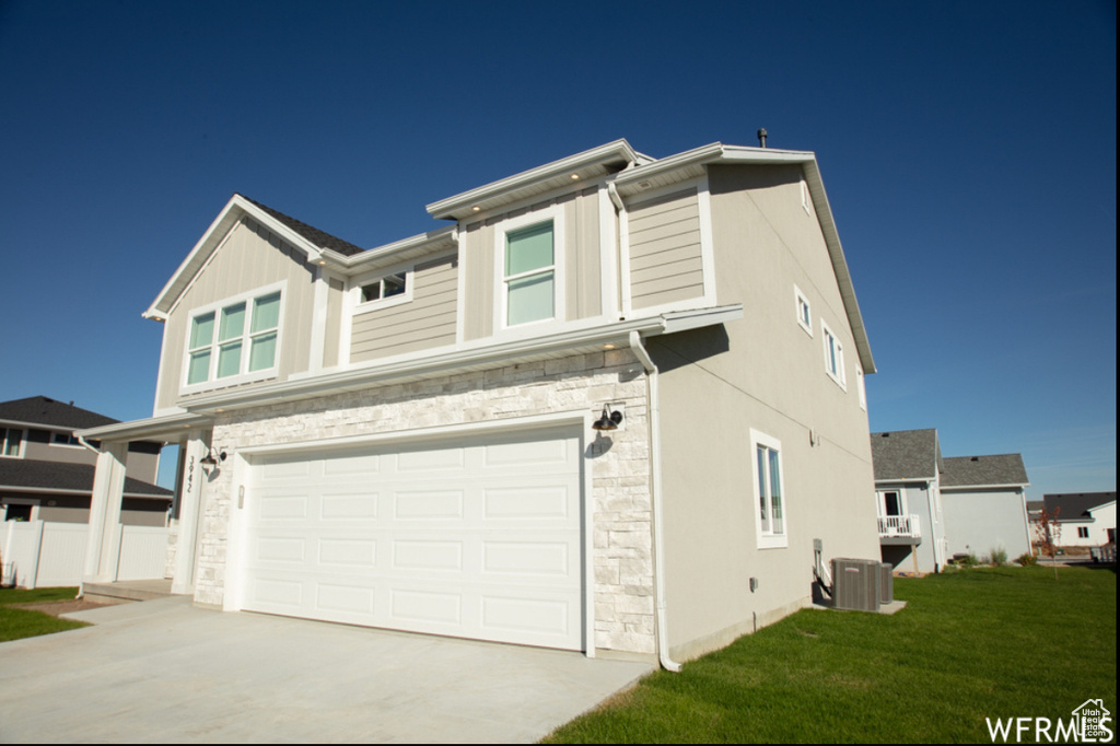 View of front facade with stone siding, a garage, concrete driveway, and a front lawn